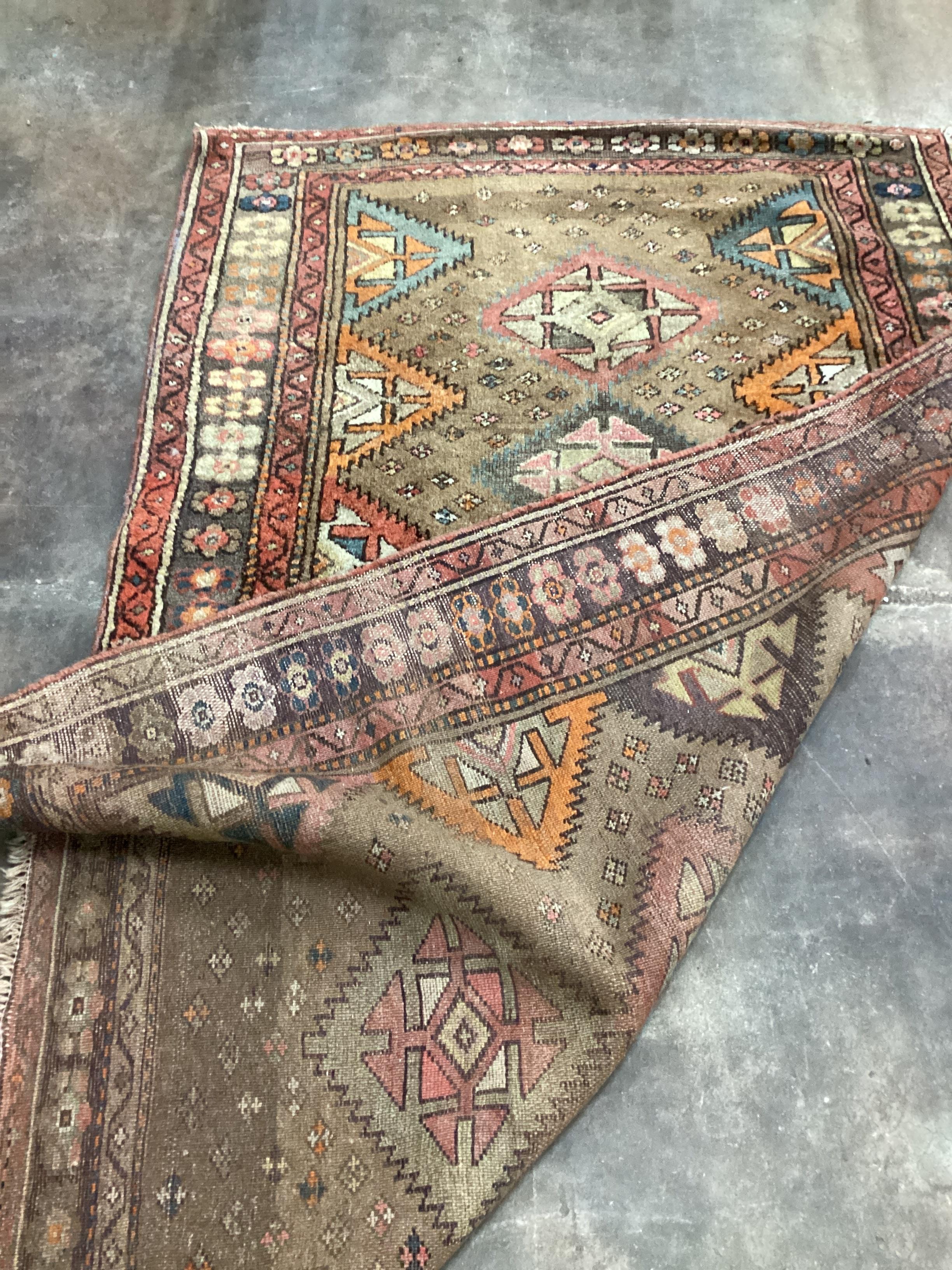 A Caucasian rug with geometric motifs on brown ground, 200 x 122cm